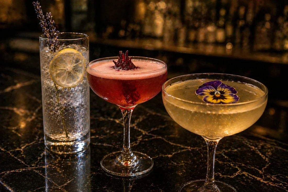 Three cocktails garnished with different edible flowers