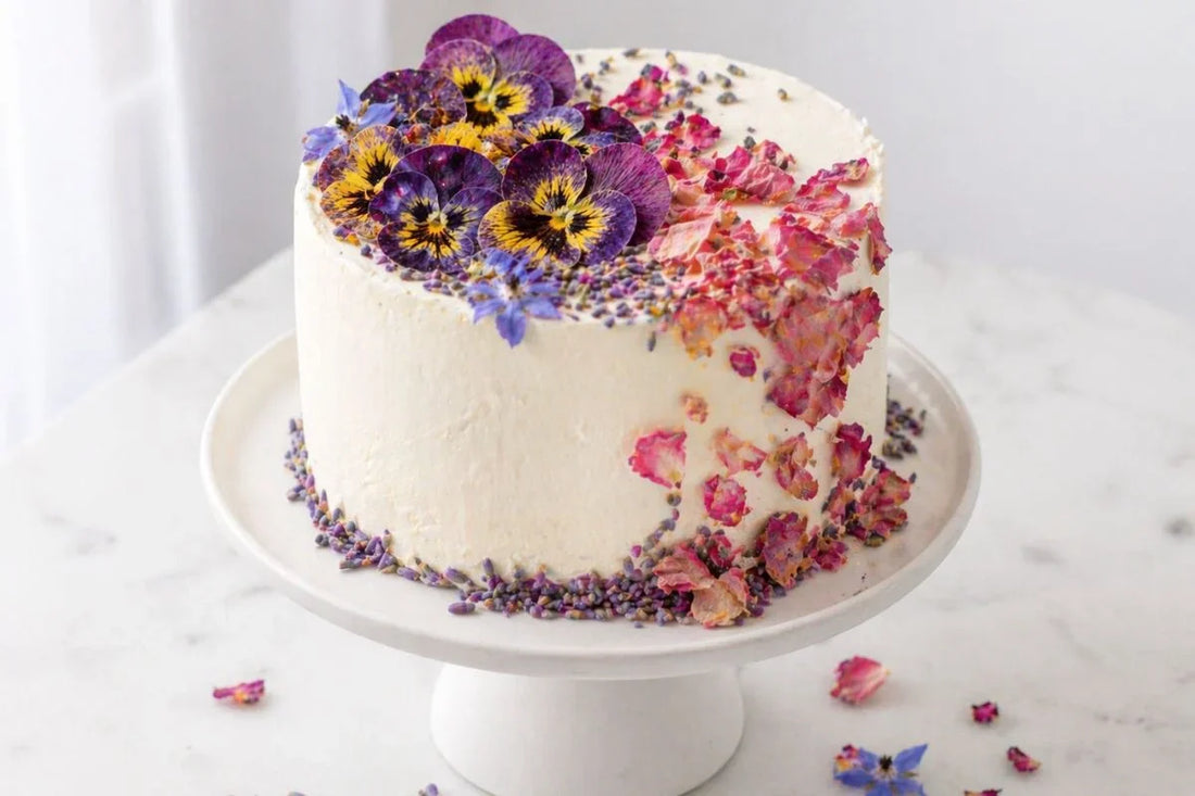 White buttercream edible flower cake on display stand